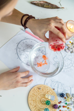 Ceromancy wax divination ritual with astrological charts, crystals, and runes on a table.の写真素材