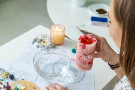 Ceromancy wax divination ritual with astrological charts, crystals, and runes on a table.