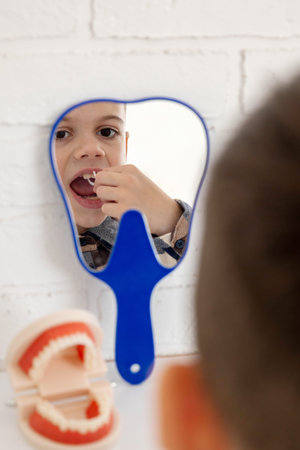Boy using dental floss pick in mirror.