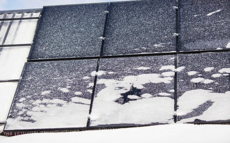 Solar panels covered with snow and ice in winter, renewable energy in frostの写真素材