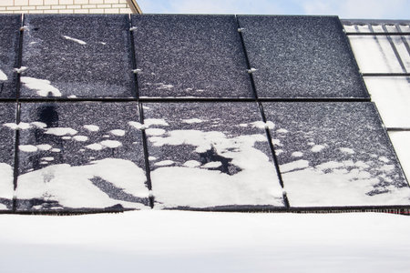 Solar panels covered with snow and ice in winter, renewable energy in frost