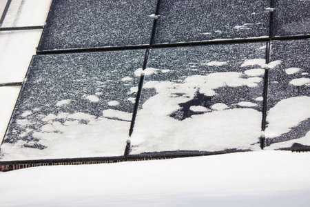Solar panels covered with snow and ice in winter, renewable energy in frostの写真素材