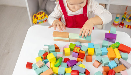 Little girl playing with colorful wooden blocks, educational games at home