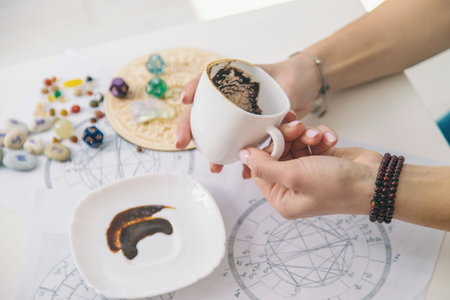 Tasseography: empty coffee cup, natal charts, runes and magic stones on table.の写真素材