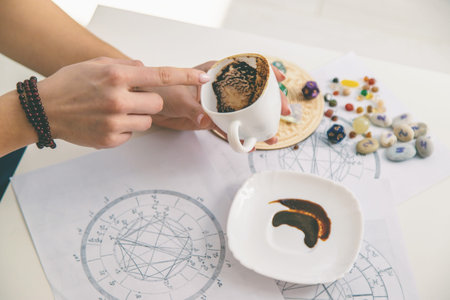Tasseography: empty coffee cup, natal charts, runes and magic stones on table.の写真素材