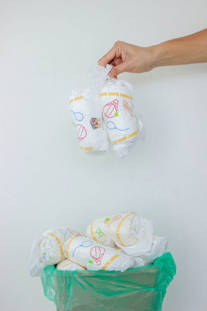 Hand used throwing diaper into trash bin, concept of hygiene and waste disposal.の写真素材