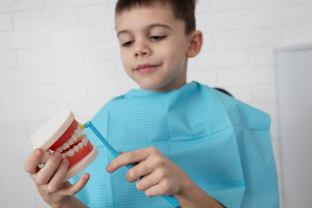 Boy brushing a dental jaw model, learning pediatric oral hygiene at the clinic.