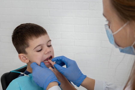 Child pointing at tooth to dentist during consultation, pediatric dental checkup.の写真素材