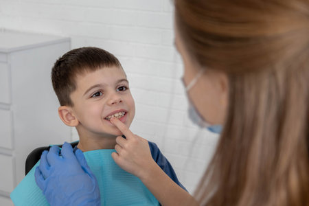 Child pointing at tooth to dentist during consultation, pediatric dental checkup.の写真素材