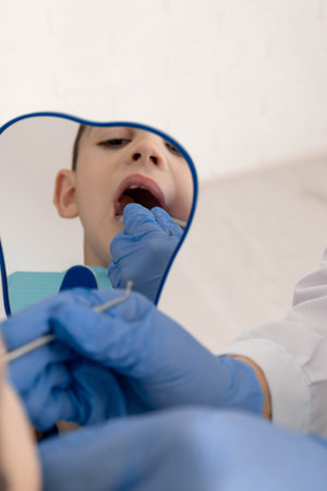Child looking in mirror during dental checkup at clinic, pediatric dentistry concept.の写真素材