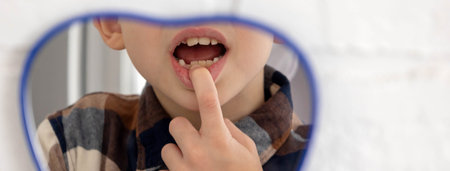 Little boy looking in the mirror at his loose primary tooth