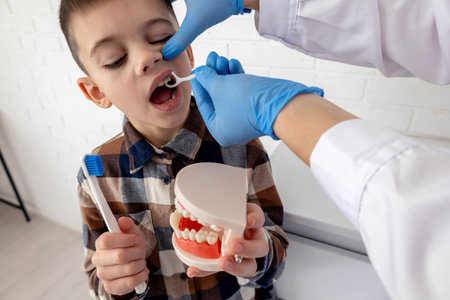 A dentist teaches a child how to use dental floss.