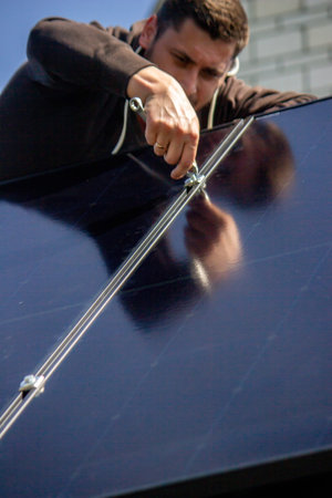 Technician installing solar panel mount on a residential house roof close up.