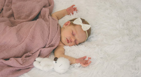 Sleeping newborn baby girl with teddy bear on white fur, banner with copy spaceの写真素材