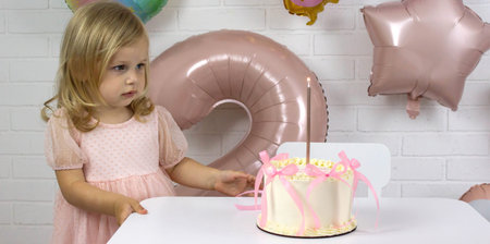 Little birthday girl with cake and pink balloons, 2nd birthday celebration
