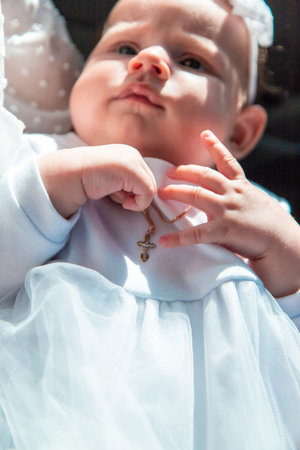 Baby's Baptism: Infant girl with a small cross necklace and white headband