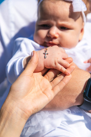 Gold cross on a palm during a baby's baptism ceremony. Happy little girl. Baptism.