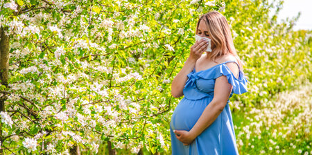 A pregnant woman in the garden of flowering apple trees is allergic. Selective focus. Nature.