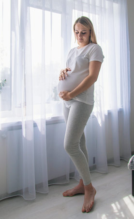 A pregnant woman looks out the window. Selective focus. People.