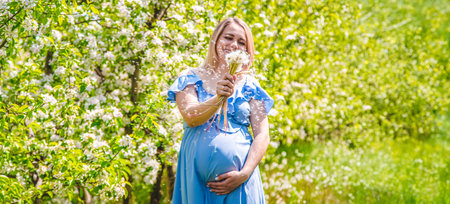 Pregnant woman with dandelions in the garden. Selective focus. Nature.