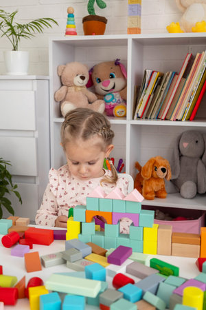 Little girl building a castle with colorful wooden blocks at home.の写真素材