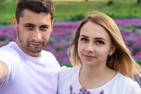 Happy young couple taking a selfie on a smartphone in a lavender field
