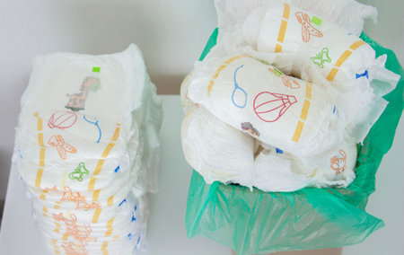 Overfilled trash can with dirty baby diapers and open lid.
