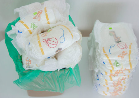 Overfilled trash can with dirty baby diapers and open lid.