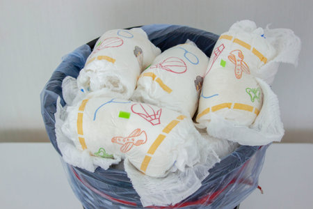Full trash bin with used dirty baby diapers, close up view.