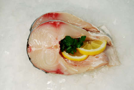 Fresh fish steaks on the ice with lemon slicesの写真素材