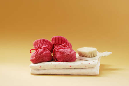 Baby booties, combs and diapers on a beige background の写真素材