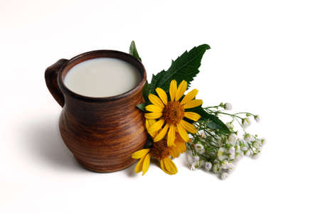 Milk in brown ceramic bowl, summer flowers on a white backgroundの写真素材