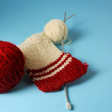 Red and white yarn balls with knitting needles on a blue backgroundの写真素材