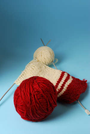 Red and white yarn balls with knitting needles on a blue backgroundの写真素材