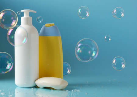 cosmetic bottles with soap bubbles over blue backgroundの写真素材