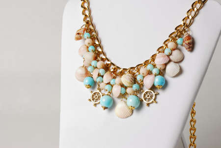 Beautiful necklace in marine style with seashells, and little wheels in front of white backgroundの写真素材