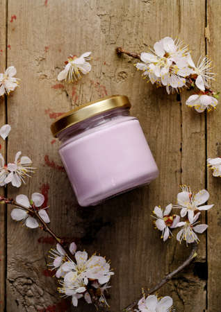 Organic cosmetic cream with apricot tree flowers on a wooden background. Vintage spa still life.の写真素材