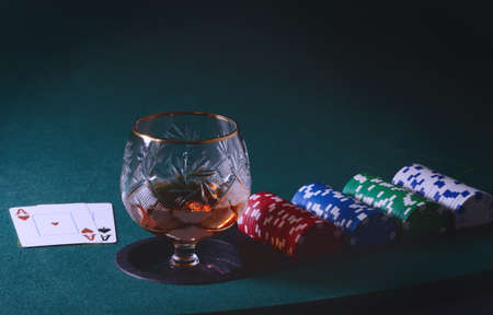 Poker table with glass of cognac or whiskey, casino chips and playing cardsの写真素材