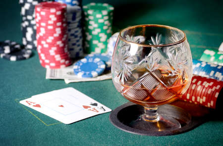 Poker table with glass of cognac or whiskey, casino chips and playing cardsの写真素材