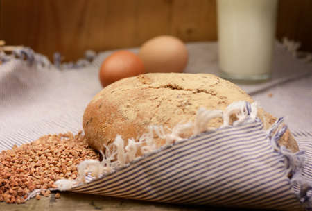 buckwheat bread glass of milk and eggs on a wooden table. Country Still Life. Vintage filterred photoの写真素材