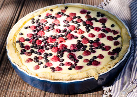 Sunny Photo with a morning breakfast in a rustic style. Cheesecake with raspberries and blueberries on wooden table. Selective focus pictureの写真素材