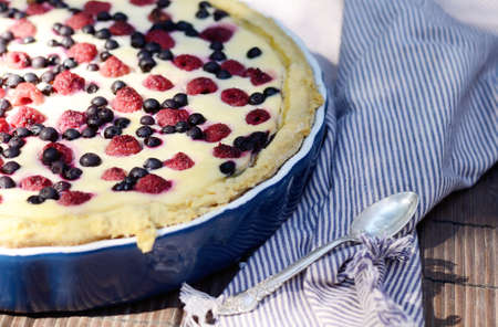 Sunny Photo with a morning breakfast in a rustic style. Cheesecake with raspberries and blueberries on wooden table. Selective focus pictureの写真素材