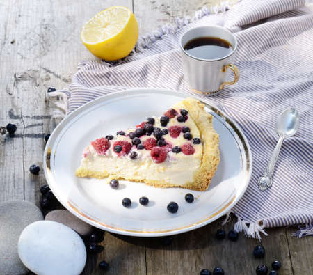 Sunny Photo with a morning breakfast in a rustic style. Cheesecake with raspberries and blueberries on wooden table. Selective focus pictureの写真素材
