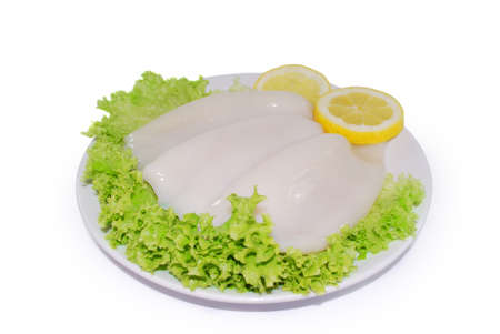 Uncooked fresh squid tubeswith lemon slices. Ocean delicacy. Isolated on a white backgroundの写真素材