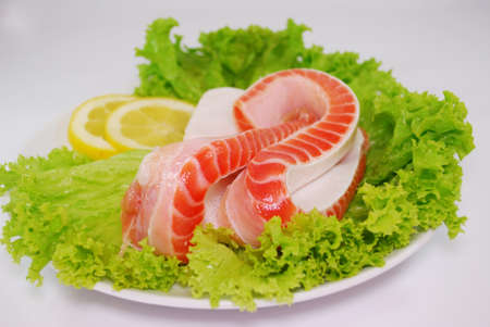 Uncooked Fresh Salmon Bellies decorated with salad and lemon slices isolated on white backgroundの写真素材
