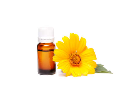 Dark cosmetic bottle of aromatic oil for herbal medicine with calendula flower isolated on white background. Marigold extract.の写真素材