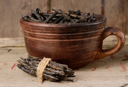 Wellness Tea drink, Bitter Twisted Leaves of Ilex Kudingcha. Green tea Kuding in a clay bowlの写真素材