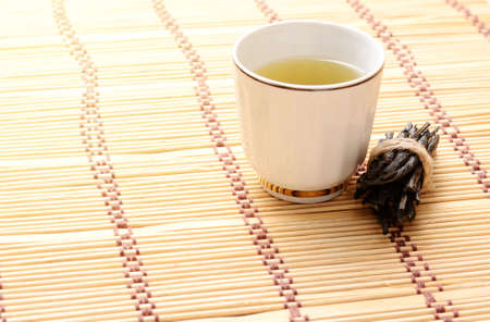 Wellness Tea drink, Bitter Twisted Leaves of Ilex Kudingcha. Green tea Kuding in a white porcelain cupの写真素材
