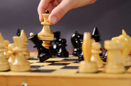 Playing chess. White queen Hitting the black one in front of the rest of the figures on the boardの写真素材
