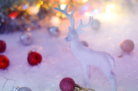 White deer figurines with bright red and white balls against lights of garland. Cozy nordic scandinavian country cottage style. Christmas card template. Winter holiday still lifeの写真素材